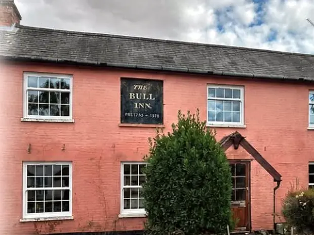 A pink-washed period cottage with new white flush casement windows and vertical sliders.