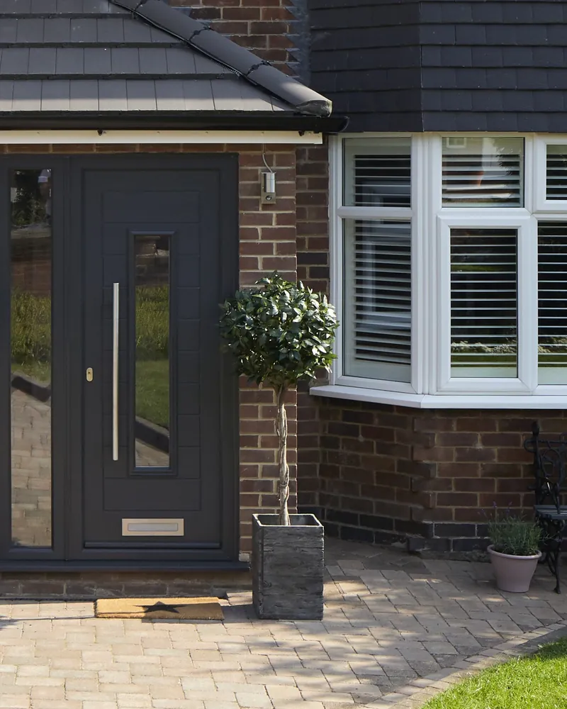 An anthracite grey Endurance front door with a slim glazed panel and a long pull handle.