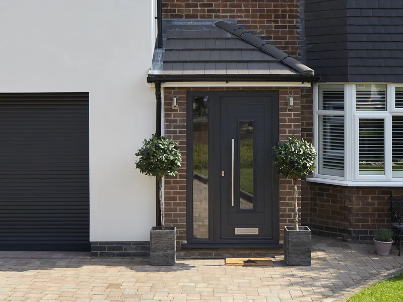 An anthracite grey Endurance front door with a long pull handle, beside a white bay window.