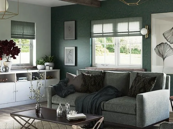 A living room with dark green walls, a grey sofa and white casement windows with Roman blinds.
