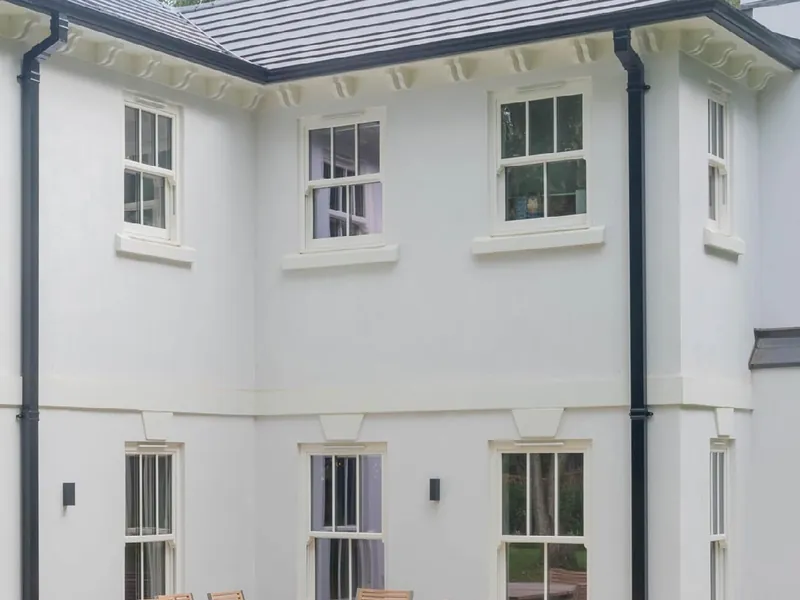 A white rendered Georgian-style house with sliding sash windows with glazing bars, on both floors.