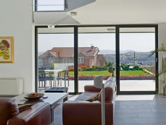 A living room with leather sofas and wide sliding doors looking out over a patio and fields.