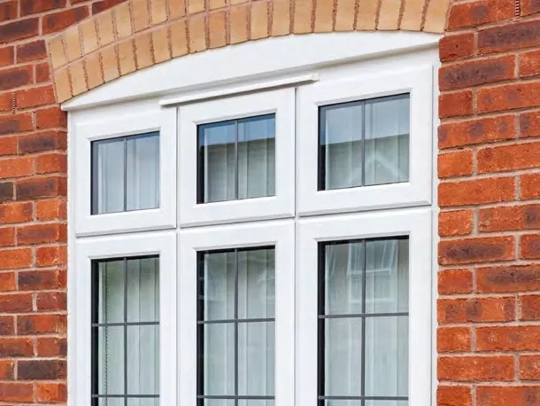 White casement windows with leaded lights, set under a curved brick arch.