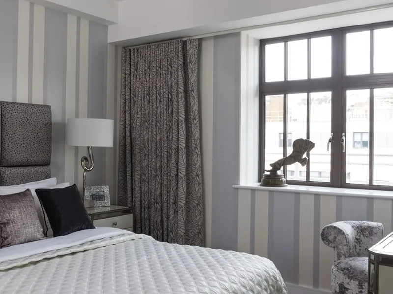 A bedroom with slim, dark, steel-look aluminium windows.