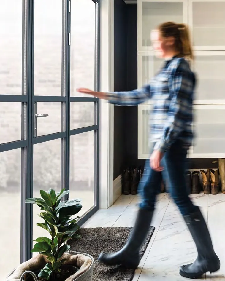 A woman walking past slim, dark, steel-look aluminium doors and glazing.