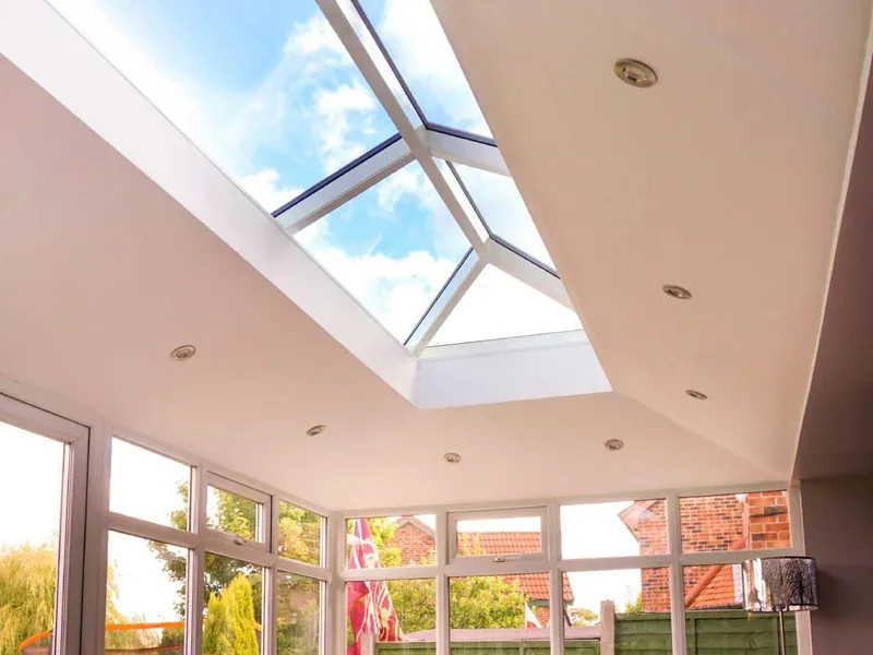 A room with a white, sloping ceiling and downlights, rising to a glass roof lantern.