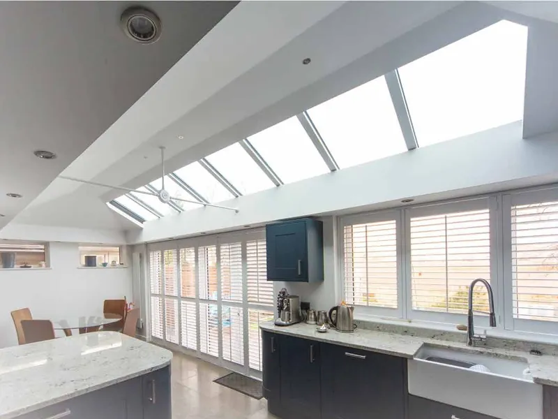 A long kitchen extension with a row of roof windows, a white worktop and a butler sink.